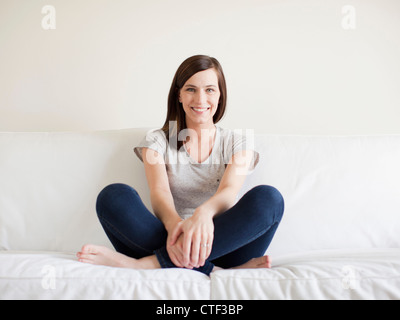 Happy young woman sitting on bed Stock Photo