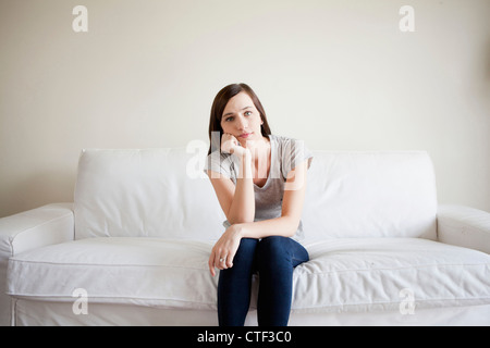Bored young woman sitting on bed Stock Photo