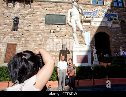 Tourists pose for souvenir snap in front of copy of Michelangelo's David in Florence. Italy Stock Photo