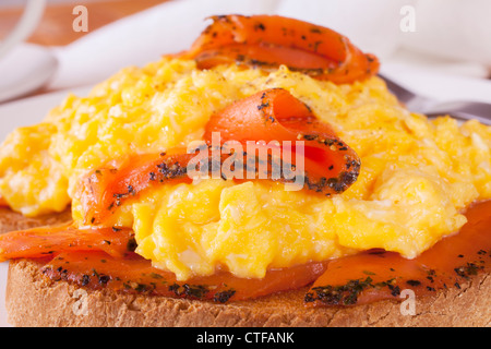 Seasoned smoked salmon with scrambled egg on toast. Stock Photo