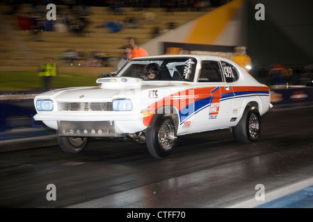 Modified and customized Ford Capri drag racing at a night race meeting. Stock Photo