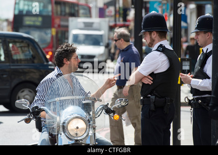 Biker on his Harley Davidson motorcycle not wearing a helmet talking to policemen. Camden high street. London Stock Photo