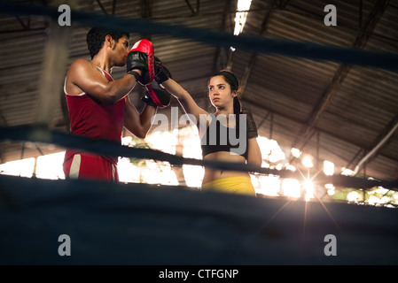 Young woman exercising with trainer at boxe and self defense lesson. Copy space Stock Photo