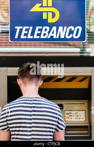 Young tourist from the UK gets cash from a Spanish cash machine (Telebanco) Stock Photo