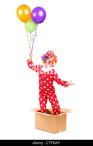 Clown holding balloons and standing in a cardboard box, isolated on white background Stock Photo