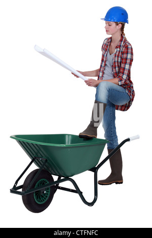 craftswoman leaning on a wheelbarrow looking at a blueprint Stock Photo