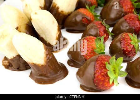 delicious strawberries and bananas covered with chocolate in a white plate Stock Photo