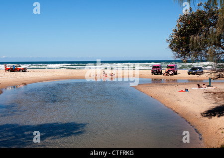 People swimming and sunbathing where Eli Creek meets the ocean on Seventy Five Mile Beach. Stock Photo