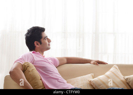 Young man day dreaming while relaxing on sofa Stock Photo