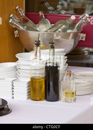 Table in a corner of a French restaurant with bottled oil and vinegar used for dressing salads and other foods Stock Photo