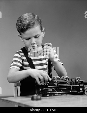 1930s 1940s LITTLE BOY FIXING LIONEL ELECTRIC TOY TRAIN ENGINE USING TOOL SCREWDRIVER Stock Photo