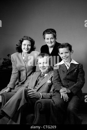 1940s PORTRAIT FAMILY MOTHER FATHER DAUGHTER SON SITTING TOGETHER ON CHAIR STUDIO Stock Photo