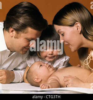 1960s FAMILY LOOKING AT NEW BABY MOTHER FATHER SISTER Stock Photo