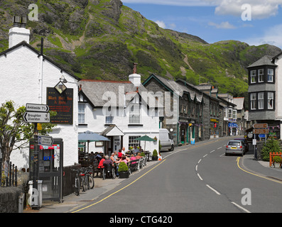 People tourist visitors outside the Black Bull Inn pub shops and cottages summer Coniston village Cumbria England UK United Kingdom GB Great Britain Stock Photo