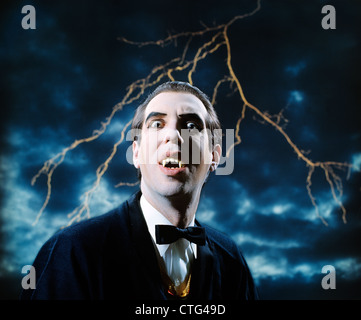 1970s DRACULA VAMPIRE CHARACTER LOOKING AT CAMERA WITH LIGHTNING IN STORMY SKY Stock Photo