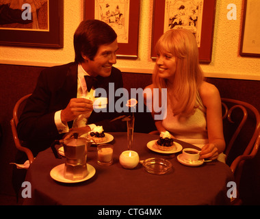 1970s COUPLE DINING ROMANTIC RESTAURANT HAVING DESSERT COFFEE BY CANDLELIGHT Stock Photo