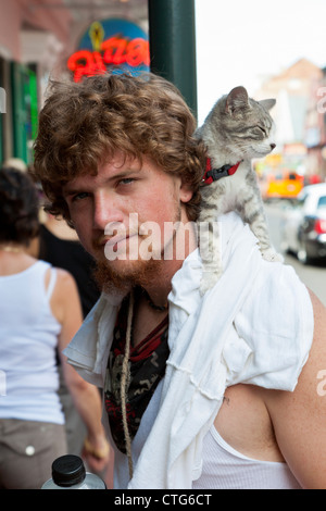 Young man walking with a cat on his shoulder in the French Quarter of New Orleans, LA Stock Photo