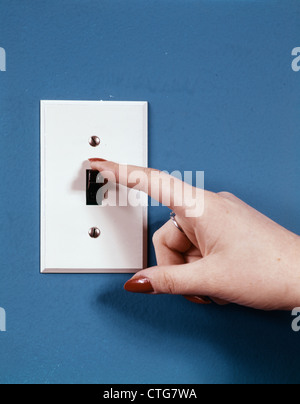 1970s FEMALE HAND WITH FINGER FLIPPING OFF LIGHT SWITCH Stock Photo