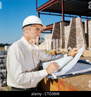 1960s MAN WEARING CONSTRUCTION HARD HAT BLUEPRINTS PLANS ENGINEER ARCHITECT Stock Photo