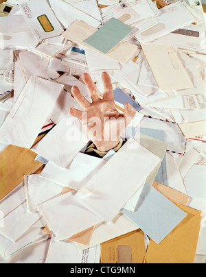 1970s 1960s MALE HAND STICKING OUT PILE MAIL BILLS LETTERS PAPERWORK DROWNING HELP DEBT Stock Photo