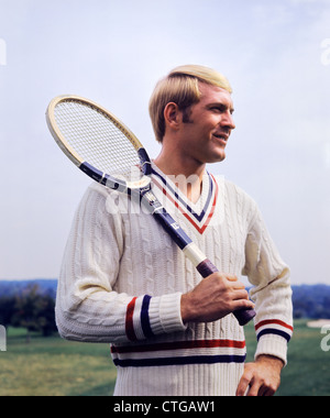 1970s SMILING BLONDE MAN WEARING CABLE KNIT SWEATER HOLDING TENNIS RACKET OVER SHOULDER Stock Photo