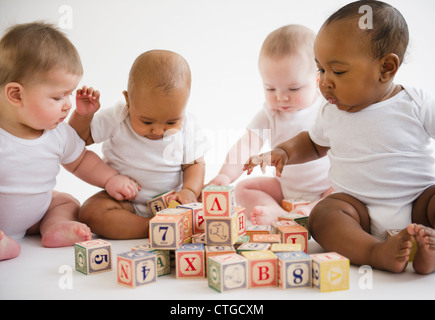 Babies sitting on floor playing with blocks Stock Photo