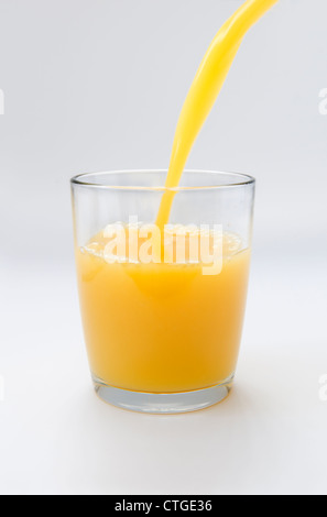 Orange juice being poured into glass on white background Stock Photo