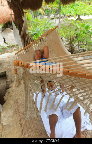 Woman enjoys massage from Maya man while lying in a hammock at Xcaret, an amusement park in Riviera Maya, Yucatan, Mexico. Stock Photo