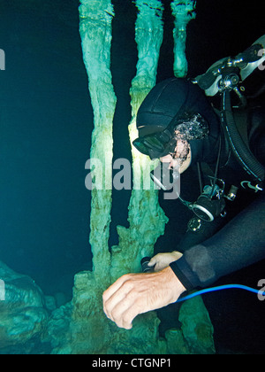 Scuba diver near one of the rock column formations in Dos Ojos, one of many cenotes where people can scuba in Akumal, Mexico Stock Photo