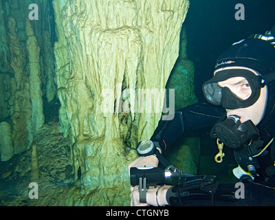 Scuba diver near one of the rock column formations in Dream Gate, one of the many cenotes where people can scuba dive in Akumal, Stock Photo