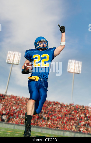 Caucasian football player running with ball Stock Photo