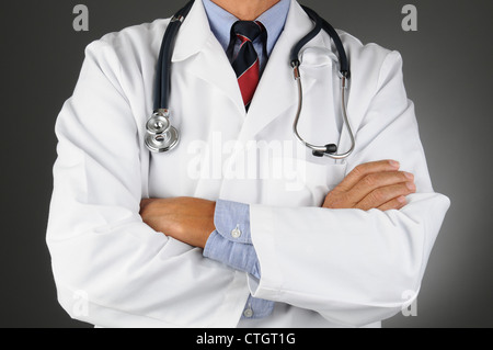 Closeup of a doctor with his arms crossed and wearing a stethoscope. Horizontal format over a light ot dark gray background. Man Stock Photo