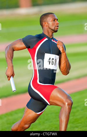 Black runner carrying baton in relay race Stock Photo