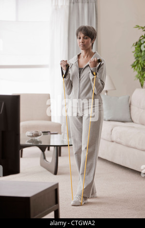 Mixed race woman exercising in living room Stock Photo