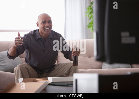 Black man drinking beer and watching television Stock Photo