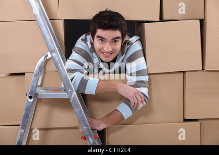 Logistics worker hiding amongst boxes Stock Photo
