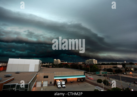 Highly detailed shelf cloud thunderstorm, showing marked green color and cloud layer delineation over a city. Stock Photo