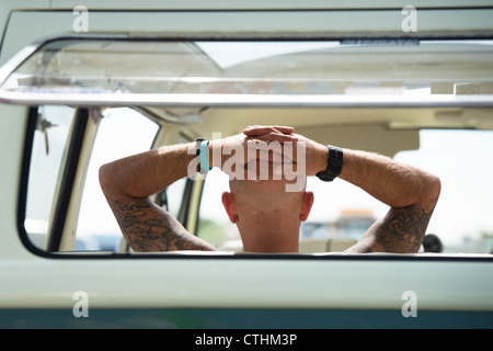 Man with hands on head relaxing in the back of a VW Volkswagen camper van Stock Photo