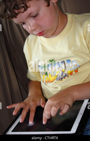 A 5 or 6 year old Caucasian boy using an iPad tablet computer wireless electronic internet device Stock Photo