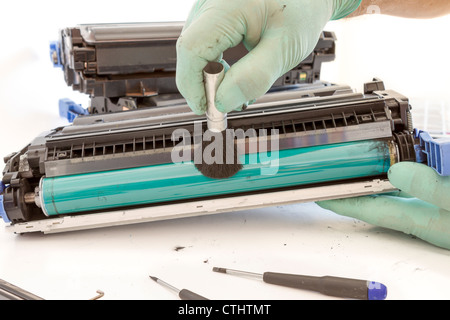 hands cleaning toner cartridge with brush the dust. worker Laser printer on a workbench. Printer workshop Stock Photo