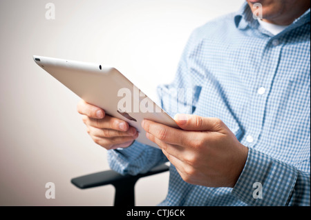 man sitting on a chair and using an iPad tablet Stock Photo