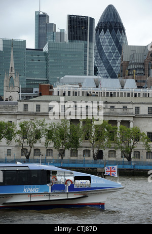 Union Jack flag on front of boat on River Thames passing the Gherkin building in London. Stock Photo