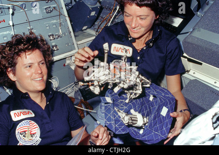 Astronauts Kathryn D. Sullivan, left, and Sally K. Ride display a sleep restraint used aboard the space shuttle while in the zero gravity of space. Stock Photo
