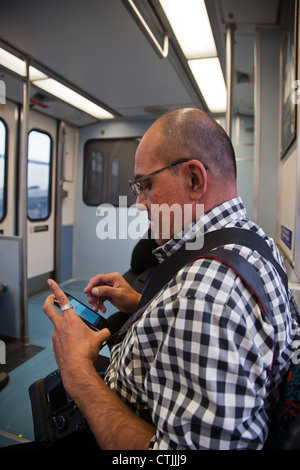 Los Angeles, California - A rider on the Los Angeles Metro Rail system uses a smart phone. Stock Photo