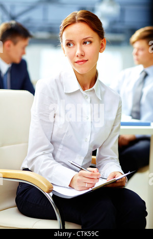 Pretty business woman with dreamy look making notes white at office Stock Photo