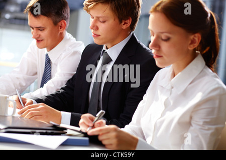 Dedicated business team writing down important information at seminar Stock Photo