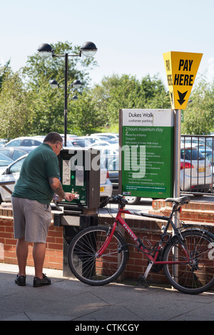 man buying parking ticket from town centre car park pay and display machine Stock Photo