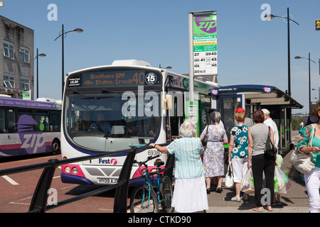 Passengers queing and boarding single decker bus at bus stop