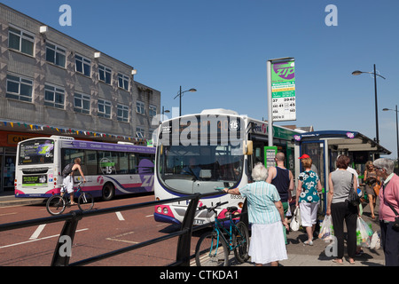 Passengers queing and boarding single decker bus at bus stop Stock Photo