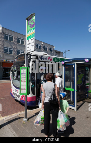 Passengers queing and boarding single decker bus at bus stop Stock Photo